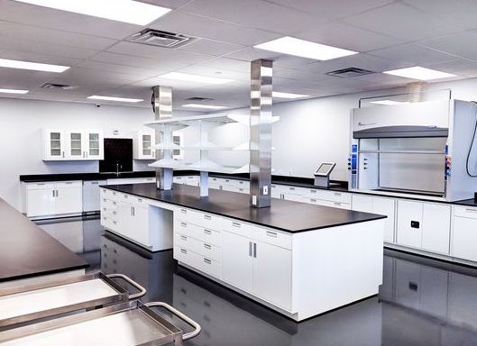 Laboratório amplo com bancadas centrais e capela de exaustão